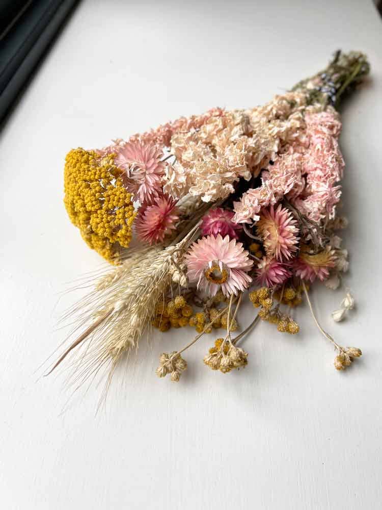 pink delphinium, yellow achilea, pink strawflower and grasses in a bunch of dried flower